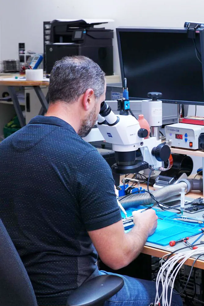 Techniker repariert ein Smartphone unter dem Mikroskop in der Werkstatt in München